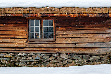 Image showing Traditional wooden cabin with thatched roof in a snowy landscape