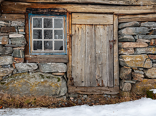 Image showing Rustic wooden cabin with stone foundation in a snowy landscape a