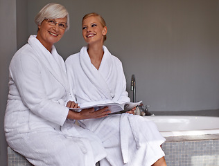 Image showing Mother, lady and smile with magazine and robe in bathroom for beauty, skincare and cosmetic treatment. Senior person and daughter on tub in spa with gown and article for wellness, hygiene and care