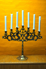 Image showing Candle, vintage and holder in church on table at interior of room or cathedral. Wax, brass and retro candlestick for decoration at temple, wood and copper metal with antique candelabra for lighting