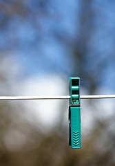 Image showing Sky, line and plastic peg or pin for clothes, outdoor and closeup of clip on rope to hang. Metal, vibrant and tool to fasten laundry to dry, clean and washing on string, backyard and sunshine