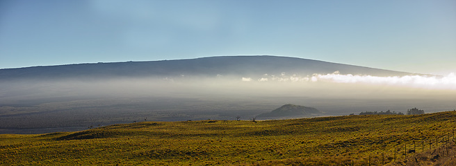 Image showing Mountain, clouds and natural landscape with field, blue sky and calm banner for travel location. Nature, fog and sustainable environment with earth, peace and holiday destination with conservation