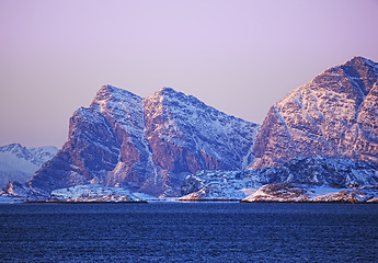 Image showing Mountain, snow and nature with ocean for blue sky, travel and outdoor adventure in cold weather. Environment, arctic and alps for winter season, remote location and vacation in ice landscape.