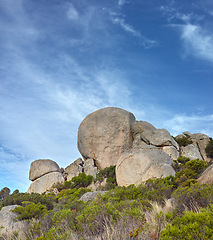 Image showing Rocks, cliff and natural landscape with blue sky, summer and calm clouds on serene peak for travel. Nature, mountain and sustainable environment with earth, tranquil hill and morning zen in ecosystem