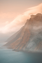 Image showing Mountain, fog and ocean landscape with cliff, cloudy sky and tropical island sunset for travel location. Nature, sea and sustainable environment with earth, natural hill and holiday destination.