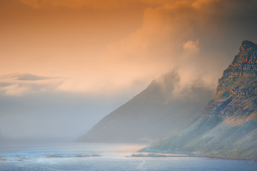 Image showing Mountain, island and ocean with sunset sky, clouds and natural landscape at travel location. Nature, ecology and sustainable environment with earth, sea and tropical holiday destination with color.