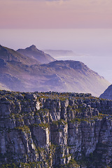 Image showing Mountain, fog and sunset sky with color on horizon, natural landscape and calm cliff at travel location. Nature, ocean and sustainable environment with earth, peace and holiday destination on island