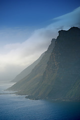 Image showing Mountain, clouds and natural island with ocean, blue sky and calm landscape for travel location. Nature, fog and sustainable environment with earth, sea and holiday destination with tropical summer