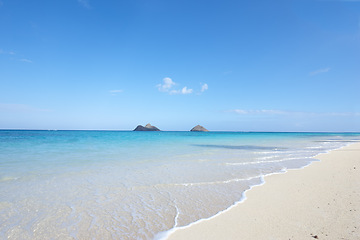 Image showing Ocean, shore and blue sky for holiday, sand and rocks in Hawaii for peace and tranquility. Seaside, waves and summer for vacation, location and beach for clear water on travel and tropical trip