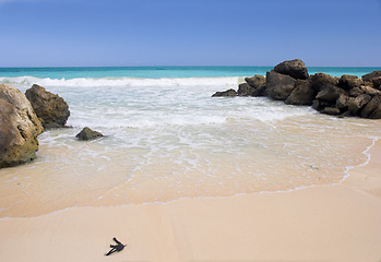 Image showing Beach, blue sky and ocean, landscape with rocks in nature and environment, sand at shore with travel destination. Horizon, waves and seascape in natural background, tropical location or island