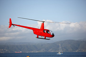 Image showing Helicopter, sea and emergency transport or landscape for search and rescue, medical service or patrol in sky. Chopper, aerial view and ocean environment for help on mountain, coast guard or lifesaver