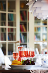 Image showing Red, wine and fruit on dinner table, celebration glasses for holiday and party in home living room. Hospitality, guest preparation with alcohol beverage, bookshelf and vacation event or entertainment