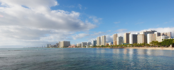 Image showing Ocean, city and buildings with landscape, travel and destination with skyscraper and nature outdoor. Urban development, architecture and environment for tourism, adventure and location with blue sky