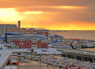 Image showing Town, harbor and sunset on sea with buildings, boats and ship on water in landscape. City, port and travel from ocean dock in Norway on ferry or yacht for holiday, vacation or adventure in summer