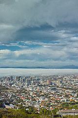 Image showing Clouds, sky and top view of city and buildings in landscape, travel destination with skyscraper and outdoor. Urban development, architecture and environment for tourism with adventure and location