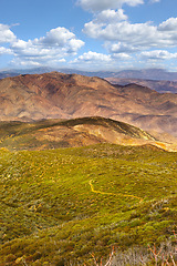 Image showing Desert, mountain and sky with clouds in nature and environment with rocks and grass for landscape outdoor. Countryside, geography and weather for season with plants and sustainable for ecology