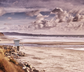 Image showing Clouds, sky and ocean by beach with sand for travel, vacation or holiday in summer. Seascape, nature and tropical island with sea, rocks and guard chair for outdoor weekend trip in Cape town.