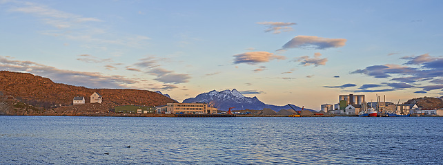 Image showing Urban, sea and sky with clouds and mountains for harbor, landmark and destination for summer season. Bodoe, attraction or site for cityscape and travel on coast for scenic and vibrant getaway or view