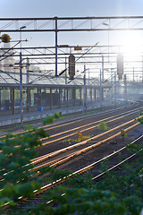 Image showing Railway, station and platform building for travel with tracks, steel infrastructure and cables with sunrise in nature. Railroad, transport industry and terminal structure for commute, transit or trip