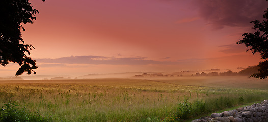 Image showing Sunlight, grass field or fog in countryside, pasture or landscape, for meadow, panorama or wallpaper. Mist, dramatic sky or sunrise for serenity, natural or colorful scenery of peaceful grassland