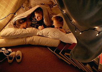 Image showing Kids, happy and sleepover in tent at night with conversation, bonding and holiday adventure or vacation. Funny friends or children by fairy lights, pillows and blanket at home for fun storytelling