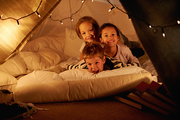 Image showing Children, happy and playing in blanket fort with portrait for fantasy, bonding and string lights at night. Friends, kids and face with smile for pajama party, sleepover and pillow tent with lighting
