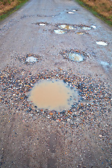 Image showing Water, gravel and rural road with pothole with maintenance, infrastructure and farm transport in winter. Dirt, path and rain puddle in hole on countryside street with damage, ground and nature.