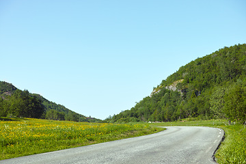 Image showing Hill, road trip and natural landscape with field, holiday or green scenery in countryside. Nature, relax and highway for journey, vacation or outdoor adventure with blue sky, trees and mountain grass