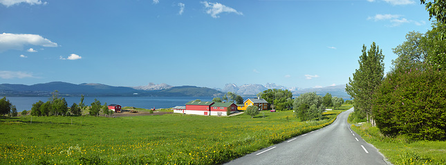 Image showing Mountain, road trip and ocean village with travel, holiday and countryside scenery in Norway. Nature, blue sky and highway for journey, vacation and outdoor adventure with lake houses, trees and bush