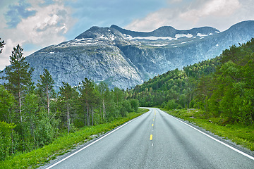 Image showing Mountain, road trip and forest highway with travel, holiday and countryside scenery in Norway. Nature, clouds in sky and street for journey, vacation and outdoor adventure with woods, trees and snow