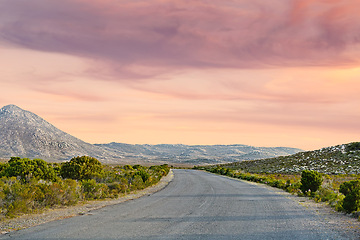 Image showing Sunset sky, road trip and red landscape with mountain, travel holiday and green countryside. Nature, environment and empty highway for journey, vacation and outdoor adventure with hill on horizon.