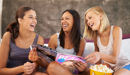 Image showing Friends, laughing and magazine on bed with happiness, girls night and entertainment in home with popcorn. Women, paper and excited with snack in house for bonding, conversation and activity together