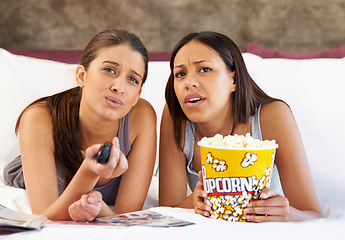 Image showing Television, remote control and confused women on a bed with popcorn, movie or film in their home together. Watching tv, face and friends in a bedroom with theatre snack for Netflix, video or show