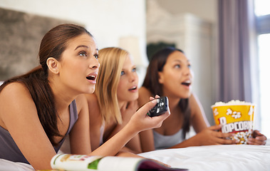 Image showing Surprise, watching tv and friends eating popcorn in bedroom for streaming show, relax or amazed together at home. Television, food or group of women with shock in bed for movie, film and wow at party
