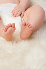 Image showing Baby feet, cute and toes in bedroom, blanket and playtime in diaper for child development in skin care. Infant, kid and wellness for newborn, adorable and rug in house for home and toddler fun