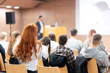 Image showing Speaker giving a talk in conference hall at business event. Rear view of unrecognizable people in audience at the conference hall. Business and entrepreneurship concept.