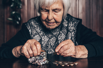 Image showing Portrait of an old woman counting money. The concept of old age, poverty, austerity.