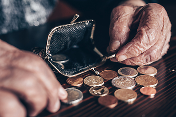 Image showing Detailed closeup photo of elderly 96 years old womans hands counting remaining coins from pension in her wallet after paying bills. Unsustainability of social transfers and pension system.