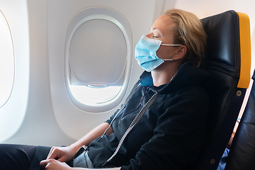 Image showing A young woman wearing face mask is traveling on airplane , New normal travel after covid-19 pandemic concept.