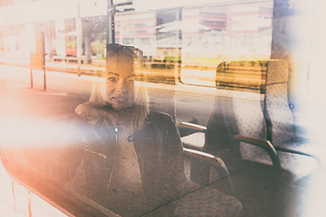 Image showing Woman traveler contemplating outdoor view from window of train. Young lady on commute travel to work sitting in bus or train.