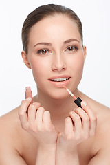 Image showing Woman, face and lipstick or makeup and beauty with gloss, shine and cosmetology on white background. Hands, portrait and cosmetic product for lips, change or transformation in studio with wellness