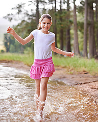 Image showing Little girl, smile and countryside in stream with happiness, feet and game of walking. Child, cute and playing in nature with joy, carefree and freedom on warm summer, water splash and energy