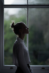 Image showing Woman, profile and window for in home, dark room and mysterious aesthetic for hopeful or artistic pose. Female artist, dim light and dream or thinking, weather and night setting in overcast at house