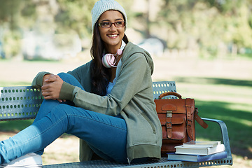 Image showing Thinking, student and woman in park with books for studying, learning and reading outdoors. Education, happy and person with bag, textbooks and headphones relax on bench for university or college