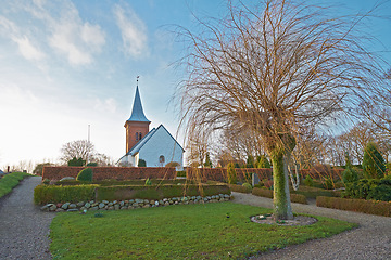 Image showing Village church, graveyard or garden architecture for medieval christianity, landscape or historical building in Denmark. Chapel, place of worship or scenery and sky in nature for landmark or religion