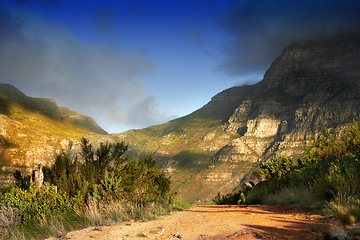 Image showing Mountains, nature and clouds in sky for travel, hiking and eco friendly tourism with dirt road, path or trail. Background of environment, landscape and bush in summer for biodiversity in Cape Town