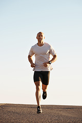 Image showing Man, running in street and fitness outdoor, cardio and health, fresh air and training for marathon with sky background. Sport, exercise and athlete in city for workout with wellness and endurance