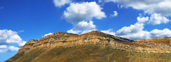 Image showing Mountain, landscape and blue sky with clouds in heaven or countryside in Africa at summer. Morning, outdoor and banner of hill on horizon with aerial view of bush environment with grass on stone