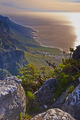 Image showing Mountain, peak and landscape at sunset with sea, plants and perspective of nature in South Africa. Hill, countryside and aerial view of valley environment with biodiversity at ocean from hiking trail