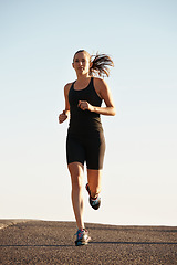 Image showing Woman, running in street and exercise for cardio, health and fresh air when training for marathon with sky background. Sports, exercise and athlete in city for workout, wellness and endurance outdoor